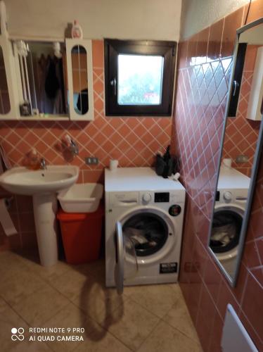 y baño con lavadora y lavamanos. en Studio flat en Golfo Aranci