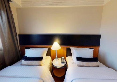 two beds in a hotel room with a lamp between them at Estanplaza International in Sao Paulo