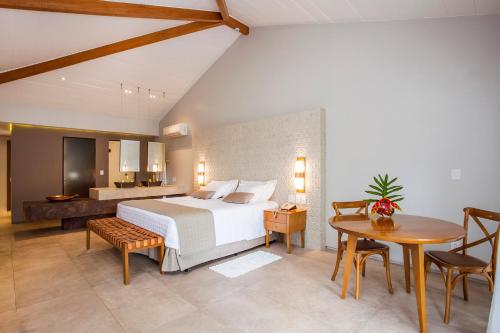 a bedroom with a bed and a table and chairs at Hotel Real Villa Bella in Ilhabela