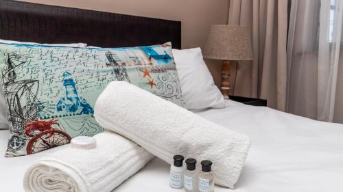 a bedroom with a bed with towels and pillows at Beach Daze in Bloubergstrand