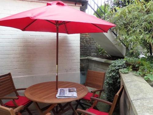 drewniany stół z czerwonym parasolem na patio w obiekcie Moray Beachside Apartments w mieście Lowestoft