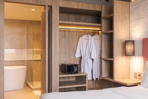 a bedroom with a closet with a bed and a tv at Novotel Porto Alegre Airport in Porto Alegre