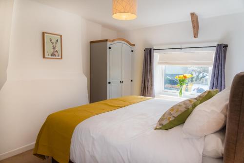 a bedroom with a bed and a window with a vase of flowers at Finest Retreats - Court Cottage in East Buckland