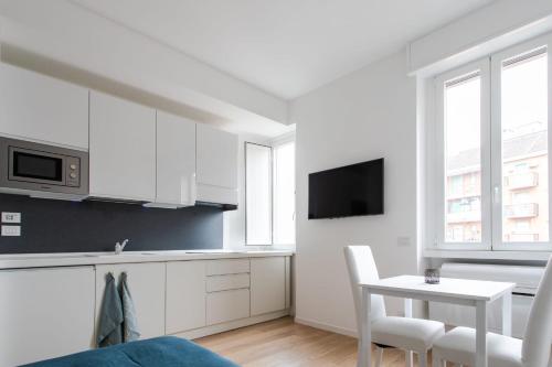 kuchnia z białymi szafkami, stołem i kuchenką mikrofalową w obiekcie Al 32 Apartment w Mediolanie