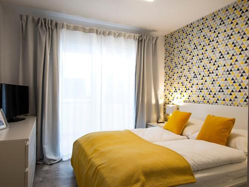 um quarto com uma cama com um cobertor amarelo e uma janela em VacationClub – Unieście-Szafirowa Mierzeja 9 em Mielno