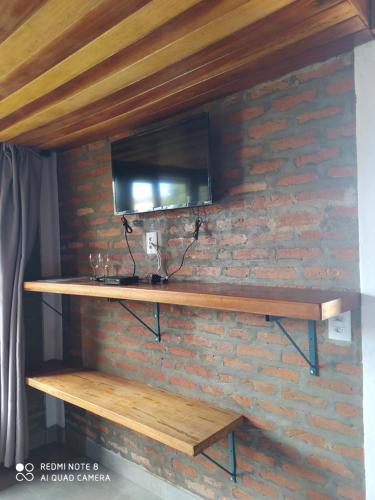 ein Regal an einer Ziegelmauer mit einem Fernseher darauf in der Unterkunft Pousada Cachoeira Esmeralda in Luminárias