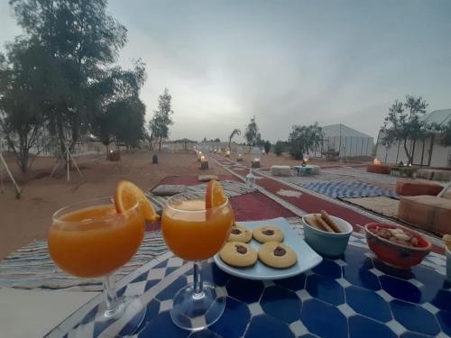 two glasses of orange juice and cookies on a table at Berber Camp in Merzouga