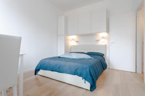 ein weißes Schlafzimmer mit einem Bett mit blauer Bettwäsche in der Unterkunft Al 32 Apartment in Mailand