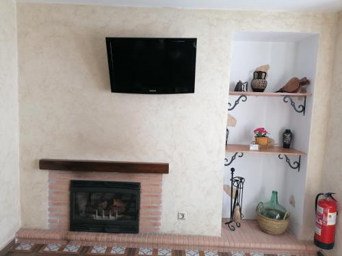 chimenea con TV de pantalla plana en la pared en La Casa de Abajo, en Setenil