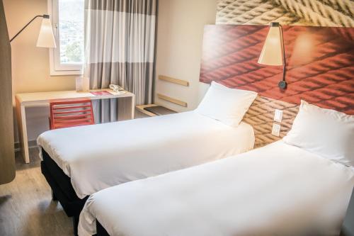 a hotel room with two beds and a desk at ibis Calama in Calama