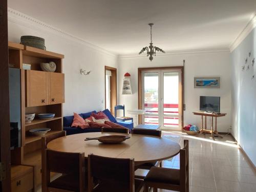 a living room with a table and a blue couch at Terraços da Vagueira in Praia da Vagueira