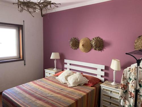 a bedroom with a bed and a purple wall at Terraços da Vagueira in Praia da Vagueira