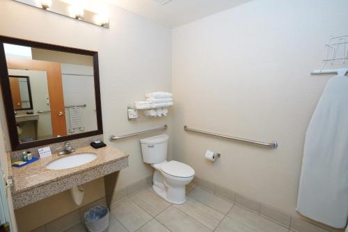 a bathroom with a toilet and a sink and a mirror at Creekside Hotel & Suites in Canyonville