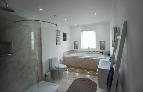 een badkamer met een bad, een toilet en een douche bij Langley Cottage with patio, spacious rooms - part of Langley Serviced Apartments several properties in Wick in Wick