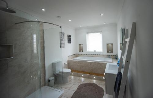 a bathroom with a tub and a toilet and a shower at Langley Cottage in Wick