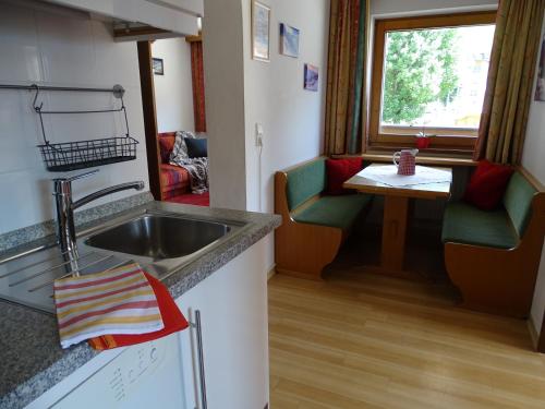 a kitchen with a sink and a table with chairs at Appartementhaus Kaltenbach-Stumm by PiaundDirk in Stumm