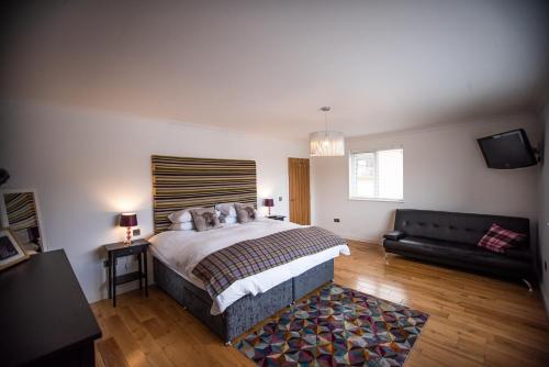 een slaapkamer met een groot bed en een bank bij Langley Cottage with patio, spacious rooms - part of Langley Serviced Apartments several properties in Wick in Wick