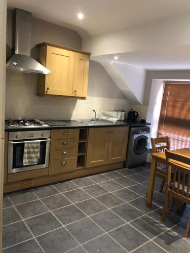 a kitchen with wooden cabinets and a table and a stove at The View in Grange Over Sands