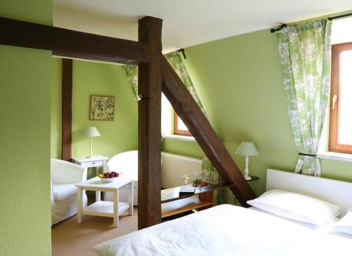 a bedroom with green walls and a bed with a ladder at Hotel Zum Gondoliere in Oranienbaum-Wörlitz