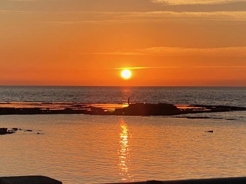 a sunset over the ocean with the sun setting at Acre sea view 11th floor apartment in ‘Akko
