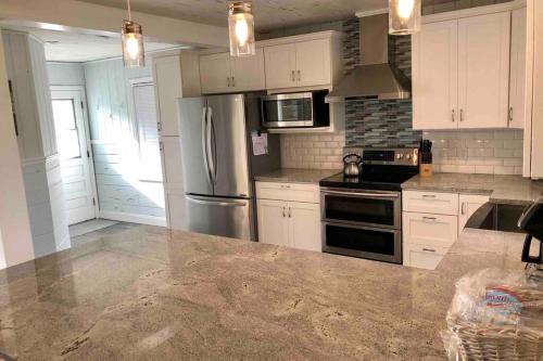 a kitchen with white cabinets and stainless steel appliances at One-of-a-kindBeach, Village, Dock & Private Pool! in Siesta Key