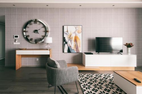 a living room with a tv and a clock on the wall at Villa Brava Atlântico in Ribeira Brava