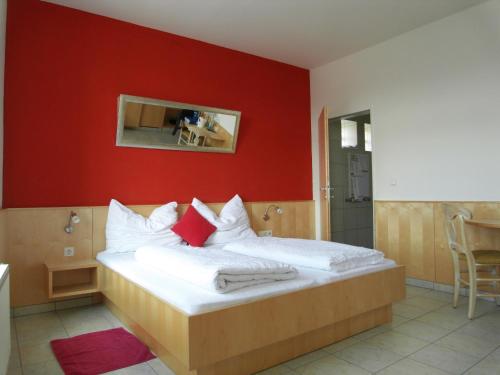 a bedroom with a bed with a red wall at Weinhotel Kirchenwirt in Gols