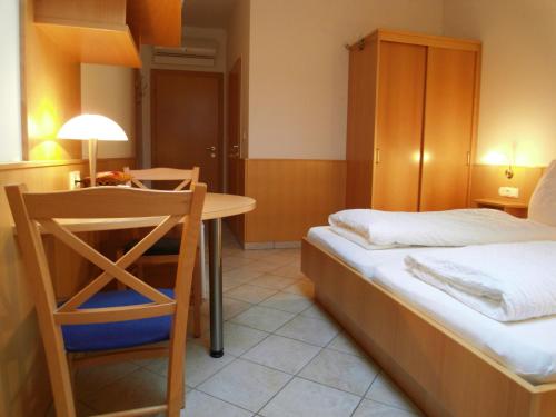 a small room with a bed and a table and a chair at Weinhotel Kirchenwirt in Gols