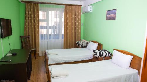 マハチカラにあるГостиница Каспийのベッド2台、デスク、窓が備わる客室です。