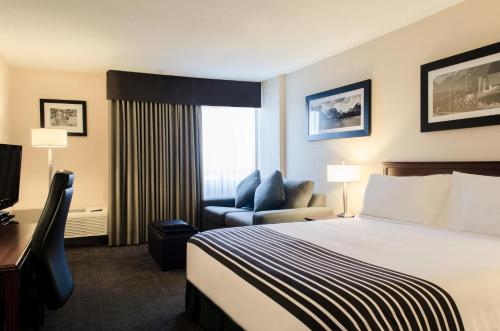 um quarto de hotel com uma cama e uma cadeira em Sandman Hotel Lethbridge em Lethbridge