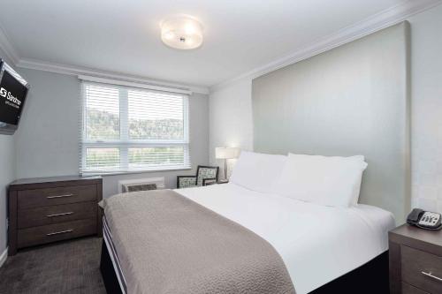 a bedroom with a large white bed and a window at Sandman Hotel & Suites Kelowna in Kelowna