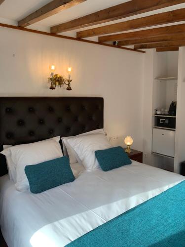 a bedroom with a large white bed with two blue pillows at Hotel Casa Bougainvillea in Sóller