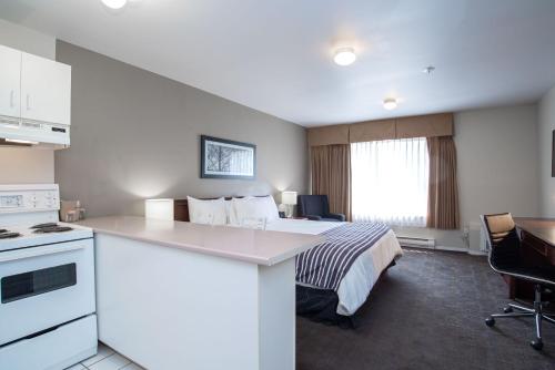 a hotel room with a bed and a kitchen at Sandman Hotel & Suites Williams Lake in Williams Lake