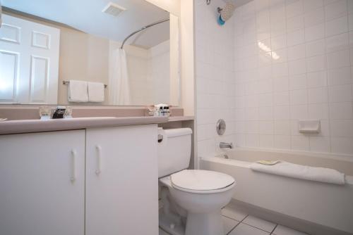 a white bathroom with a toilet and a bath tub at Sandman Hotel & Suites Williams Lake in Williams Lake
