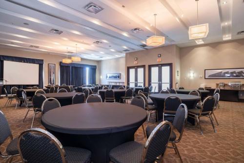 a conference room with tables and chairs and a screen at Sandman Hotel & Suites Winnipeg Airport in Winnipeg