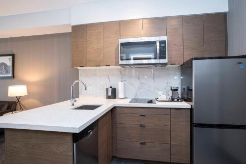 a kitchen with a refrigerator and a microwave at Sandman Signature Sherwood Park Hotel in Sherwood Park