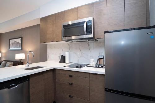 a kitchen with a stainless steel refrigerator and a microwave at Sandman Signature Sherwood Park Hotel in Sherwood Park