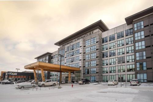 a large building with cars parked in a parking lot at Sandman Signature Sherwood Park Hotel in Sherwood Park
