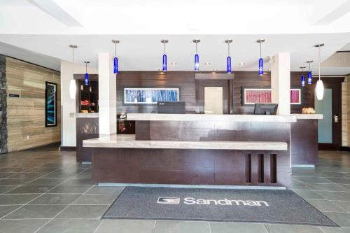 a lobby with a bar in a building with blue pendants at Sandman Hotel & Suites Prince George in Prince George