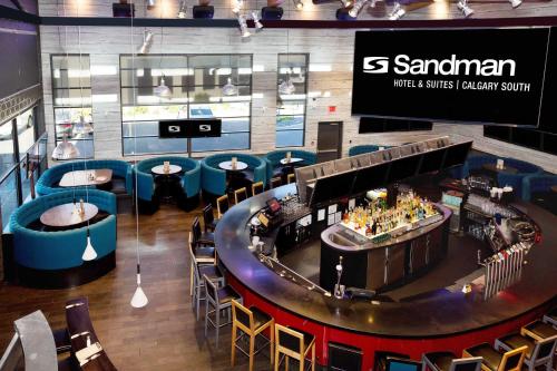 a restaurant with tables and chairs and a bar at Sandman Hotel & Suites Calgary South in Calgary
