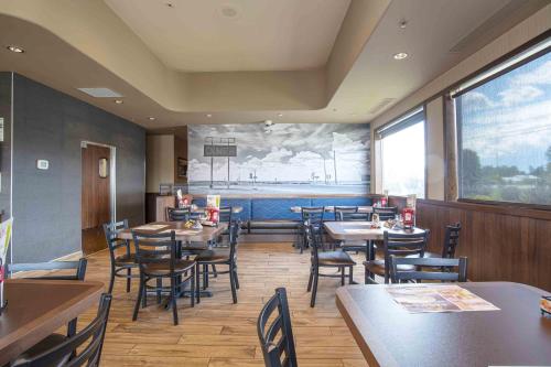 a restaurant with tables and chairs and a large window at Sandman Hotel Quesnel in Quesnel