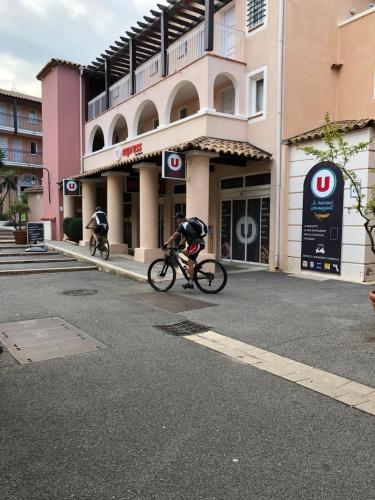 due persone che pedalano in bicicletta lungo una strada di fronte a un edificio di Roches d’azur a Saint-Raphaël