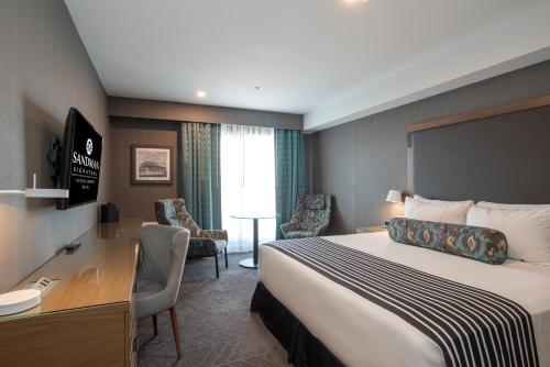 a hotel room with a bed and a desk at Sandman Signature Ottawa Airport Hotel in Ottawa