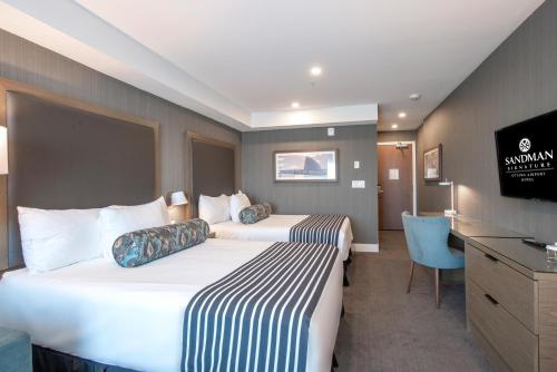a hotel room with two beds and a television at Sandman Signature Ottawa Airport Hotel in Ottawa