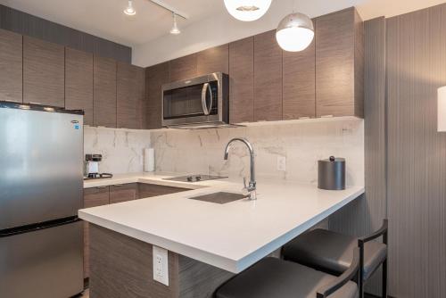 a kitchen with a sink and a refrigerator at Sandman Signature Ottawa Airport Hotel in Ottawa