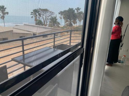 a woman standing on a balcony looking out of a window at WATERFRONT HOUSE 3 BEDROOM in Sere Kunda
