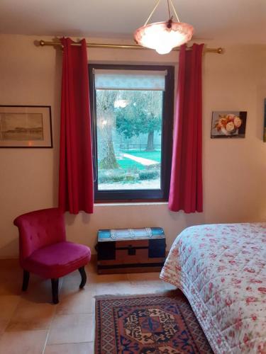 a bedroom with a bed and a window and a chair at La PASTORALE in La Puisaye