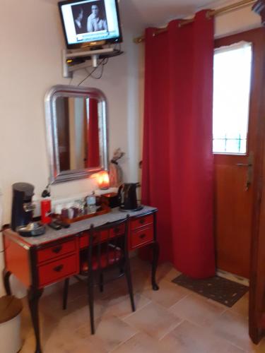 Cette chambre comprend un bureau avec un miroir et une télévision. dans l'établissement La PASTORALE, à La Puisaye