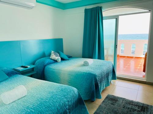 a bedroom with two beds and a balcony with the ocean at Habitación Amanecer Turquesa #2 in Isla Mujeres