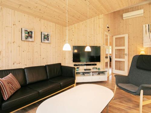 a living room with a black couch and a tv at 12 person holiday home in Hals in Hals